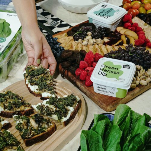 hand picks up a green harissa mushroom and ricotta toast