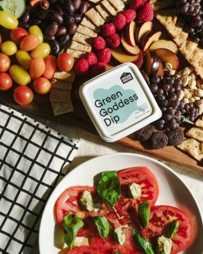 gotham green's green goddess dip container sits next to a caprese salad